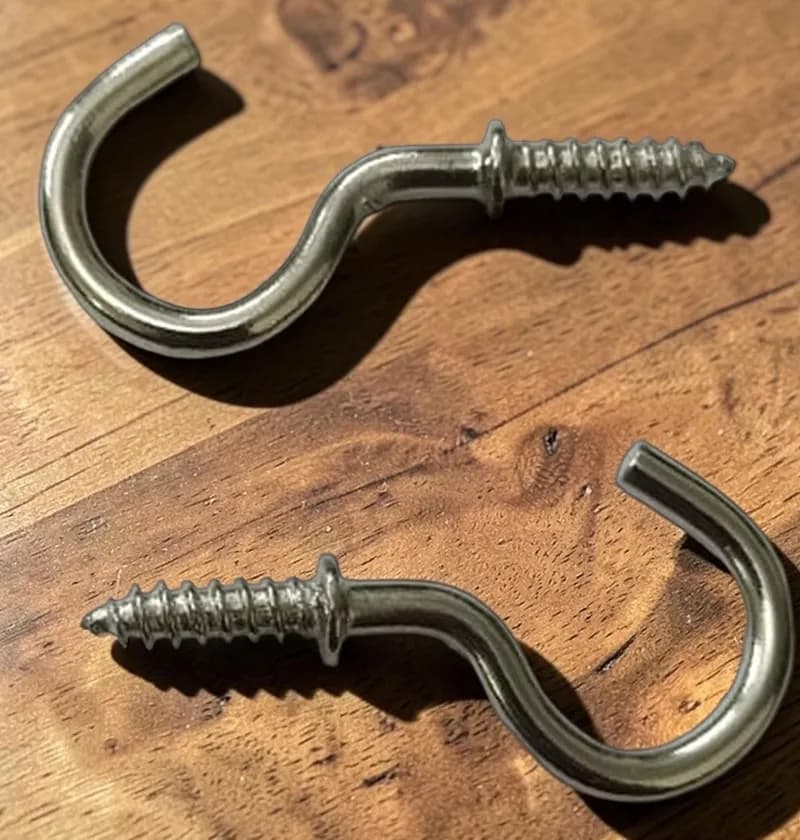 Two silver cup hooks lying on a wooden surface