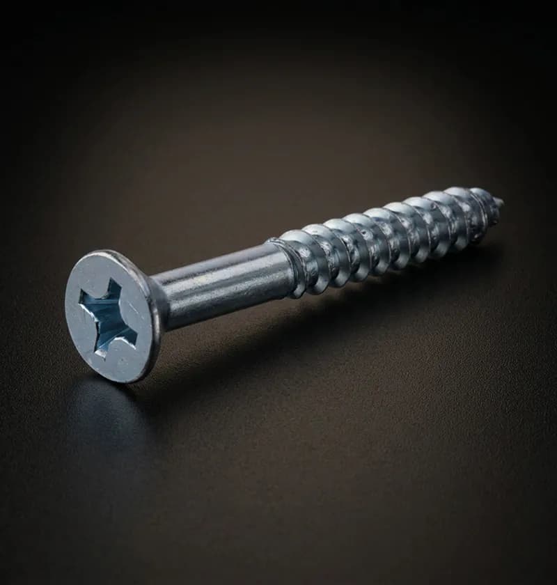 Silver Phillips head wood screw on a dark surface
